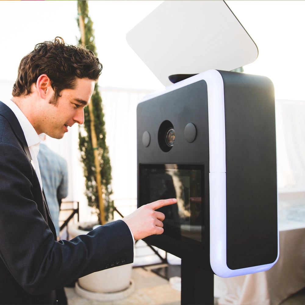 Modern photo booth machine with touchscreen interface, camera, and lighting setup, ready for capturing high-quality photos at events and parties.